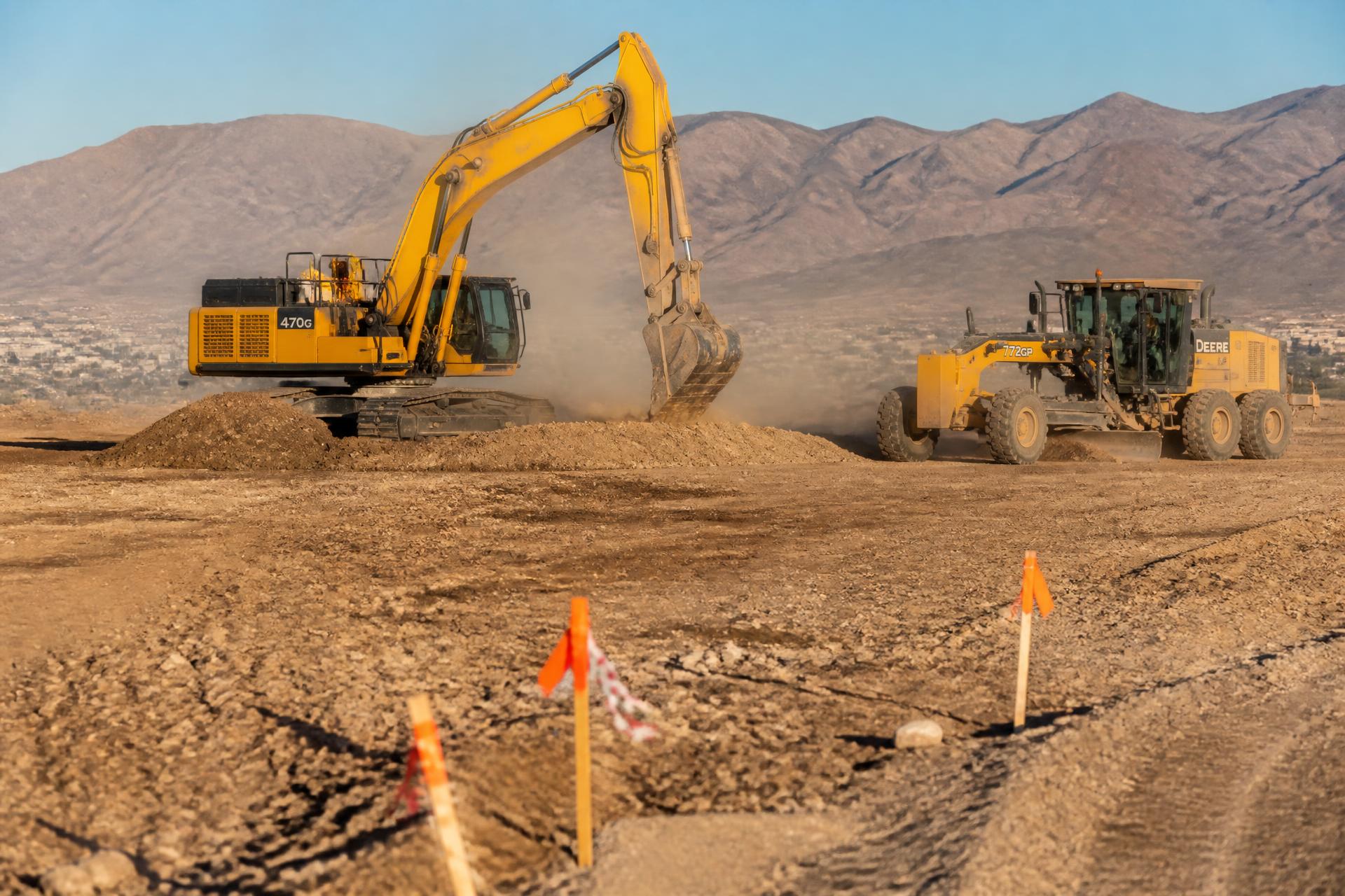 Excavator and motor grader cutting a desert building pad outside Las Vegas